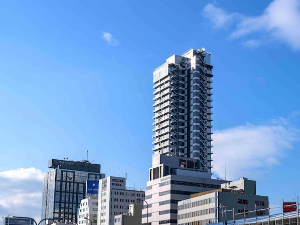 Un grand bâtiment moderne à étages, probablement un hôtel ou un immeuble de bureaux, avec un ciel bleu clair en arrière-plan.