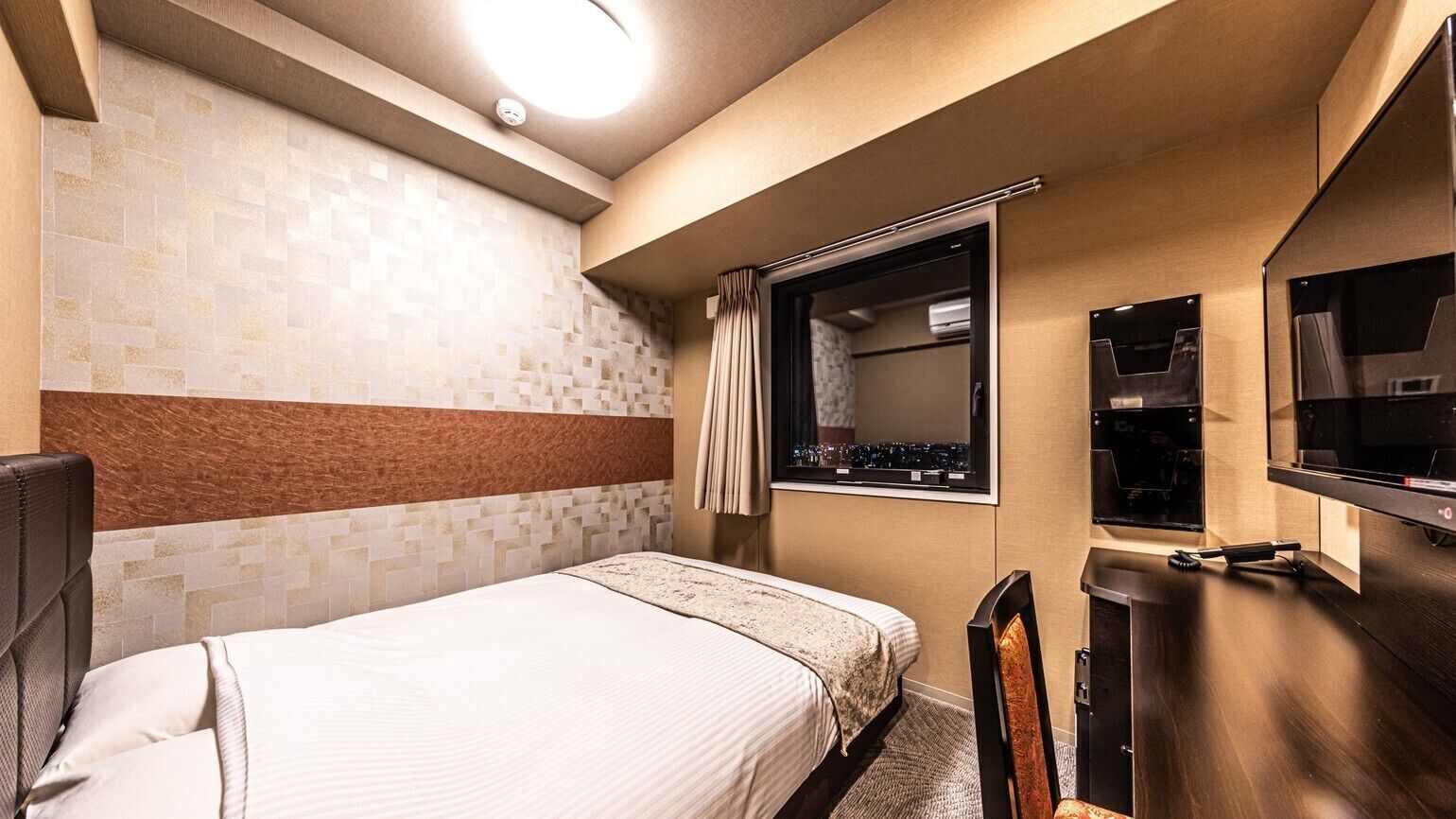 Une chambre d’hôtel avec un lit, une télévision, un miroir et une fenêtre avec des rideaux.