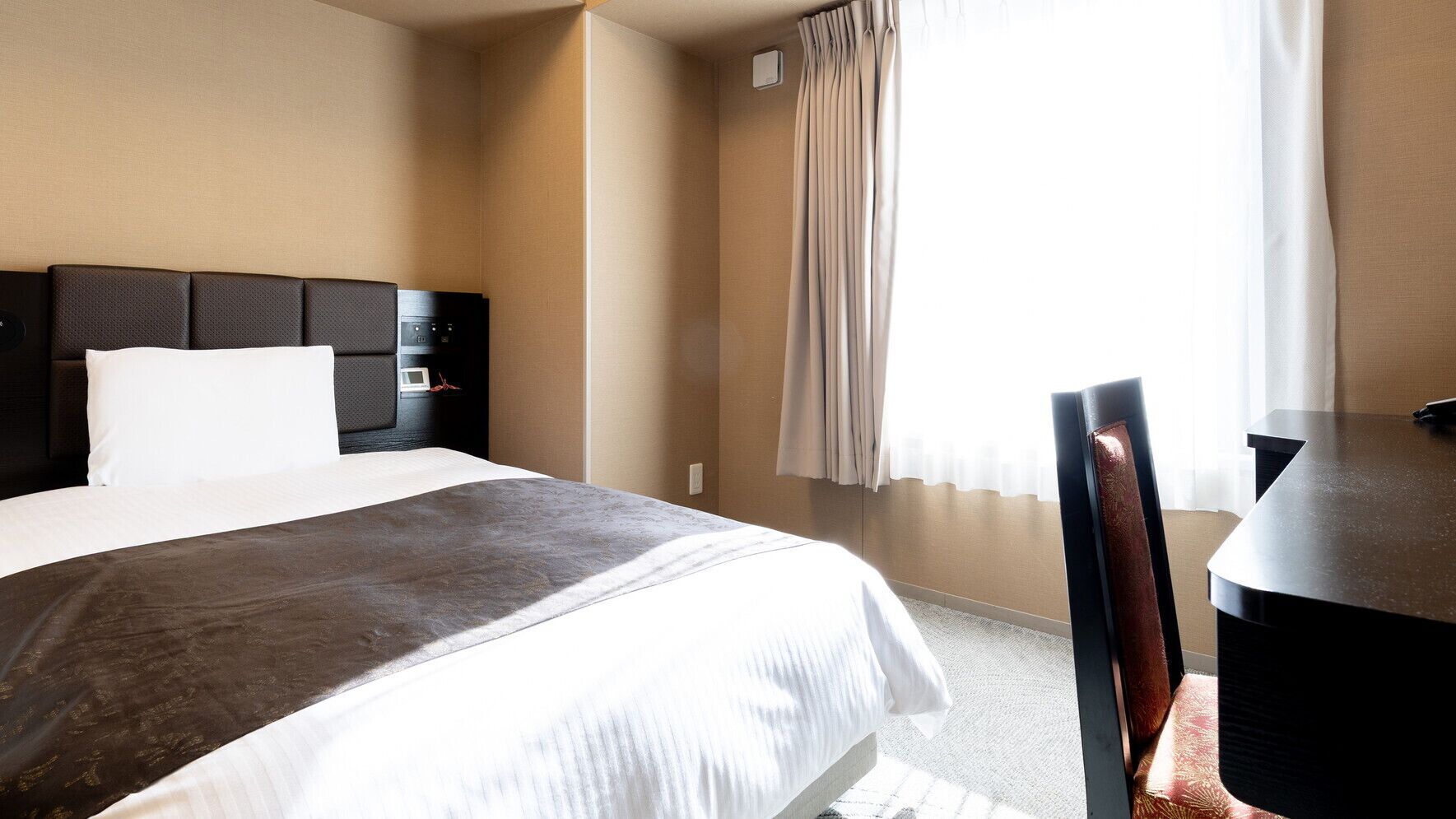 Une chambre d’hôtel avec un lit, un bureau et une chaise.