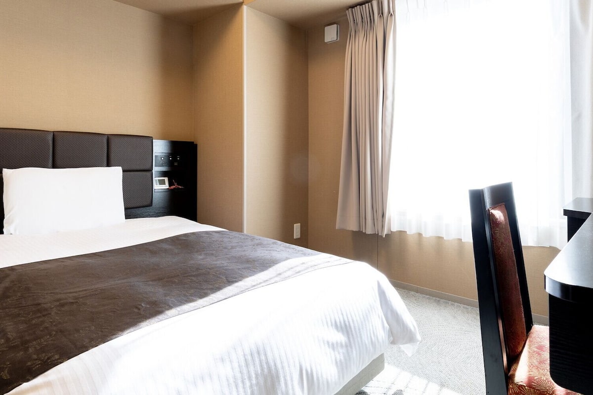 Une chambre d’hôtel avec un lit, un bureau et une chaise.