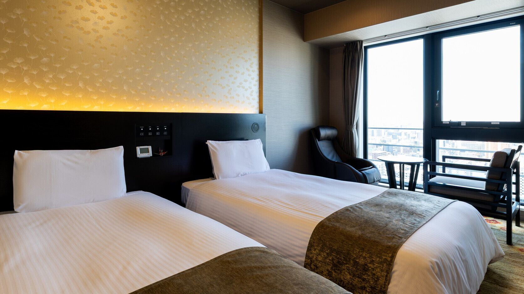 Une chambre d’hôtel avec deux lits, un panneau de commande, un fauteuil de massage et une vue sur la ville.
