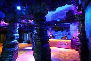 An interior with rock-like structures, a reception desk, and a digital display. - Henn Na Resort And Spa Kansai Airport (Izumisano)