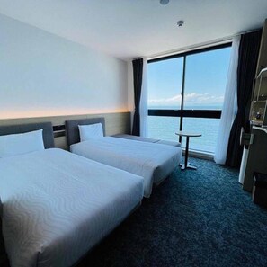 A hotel room with two beds, a small table, a view of the sea, and a window with curtains. - Henn Na Resort And Spa Kansai Airport (Izumisano)