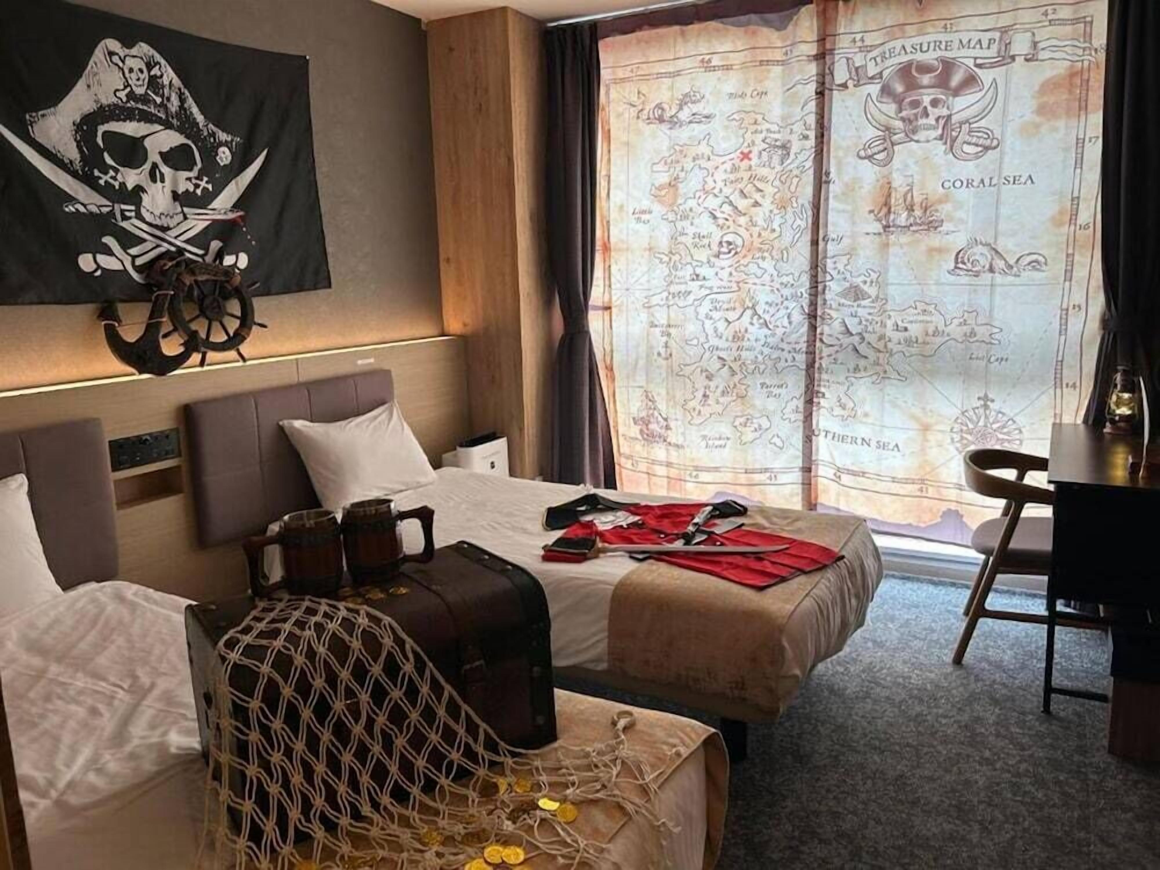 Quarto de hotel com cama, escrivaninha e uma grande janela com um mapa do Caribe.