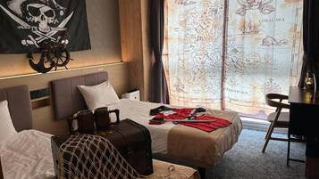 Quarto de hotel com cama, escrivaninha e uma grande janela com um mapa do Caribe.