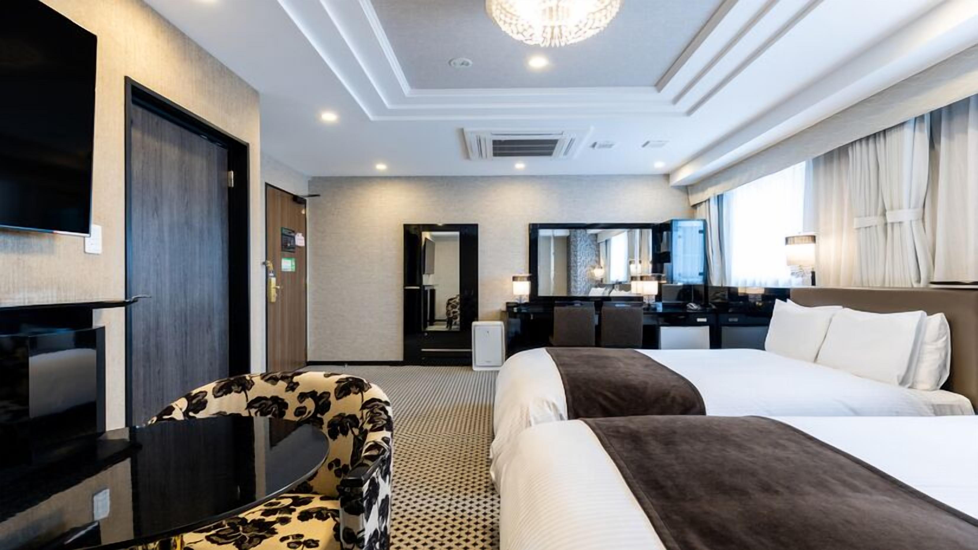 Ein Hotelzimmer mit einem Bett, einem Schreibtisch, einem Sessel, einem Fernseher und einem Spiegel.