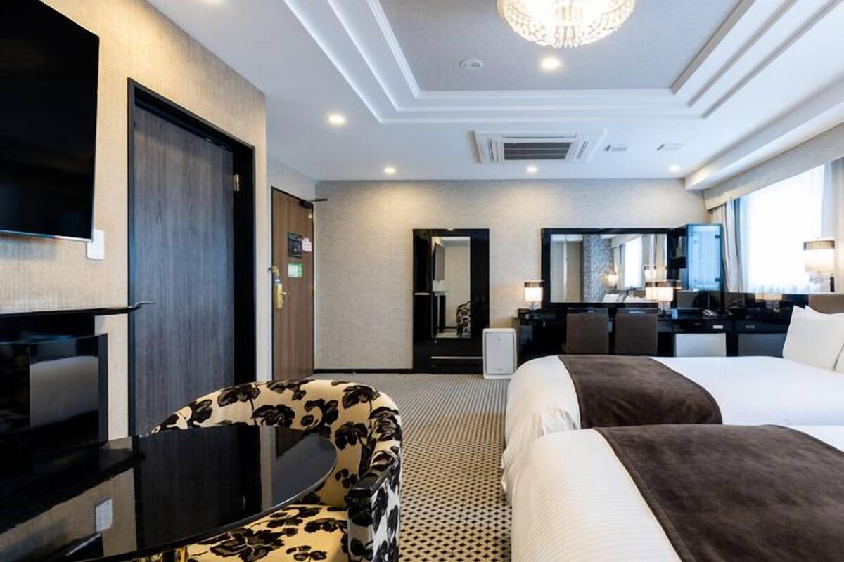 A hotel room with a bed, a desk, a chair, a television, and a mirror.