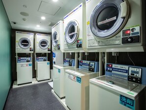 A laundry facility with multiple washing machines and dryers, each with a control panel and instructions in Japanese. - APA Hotel Resort Midosuji Hommachi Eki Tower (Osaka)