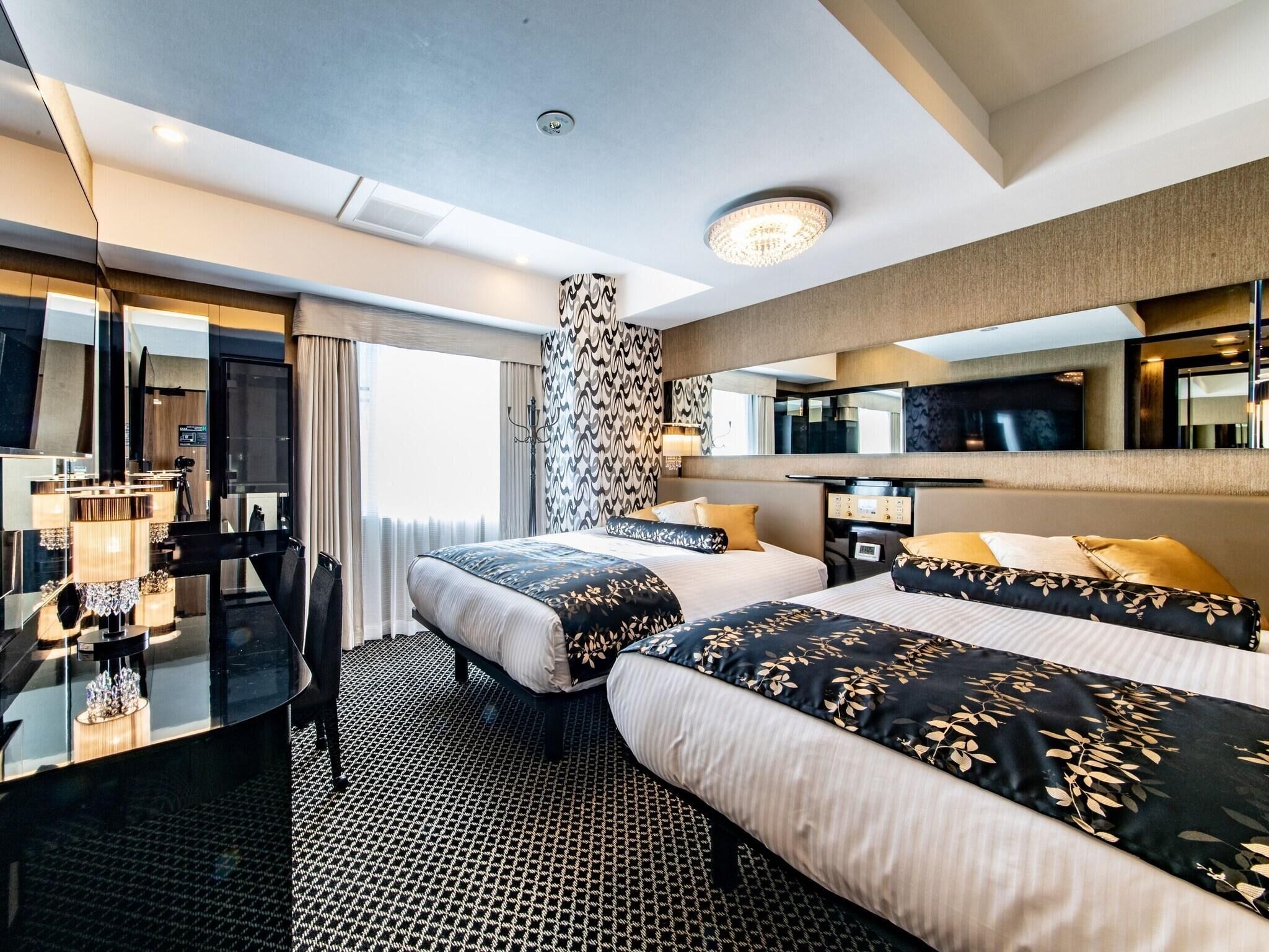 Ein Hotelzimmer mit zwei Betten, einem Schreibtisch, einem Stuhl, einem Fernseher und einem großen Spiegel.