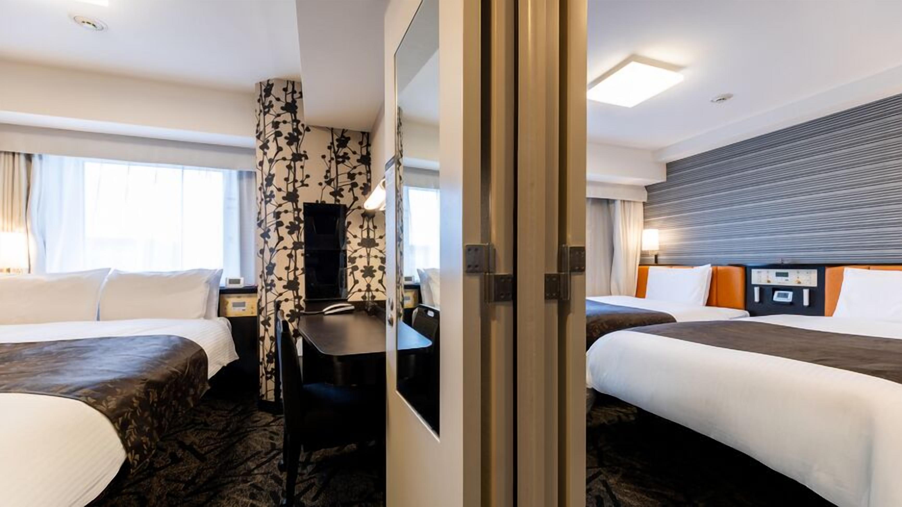 Ein Hotelzimmer mit zwei Betten, einem Schreibtisch, einem Stuhl und einem großen Fenster.