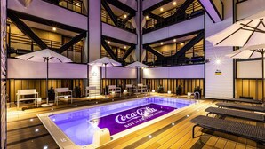 A multi-level indoor pool area with seating and umbrellas, featuring a Coca-Cola branding on the pool floor. - APA Hotel Resort Midosuji Hommachi Eki Tower (Osaka)