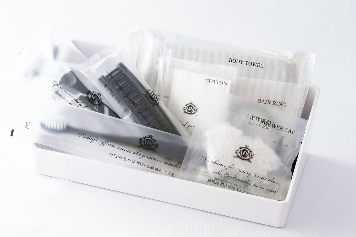 A white toiletry bag containing a body towel, hair ring, and shower cap.
