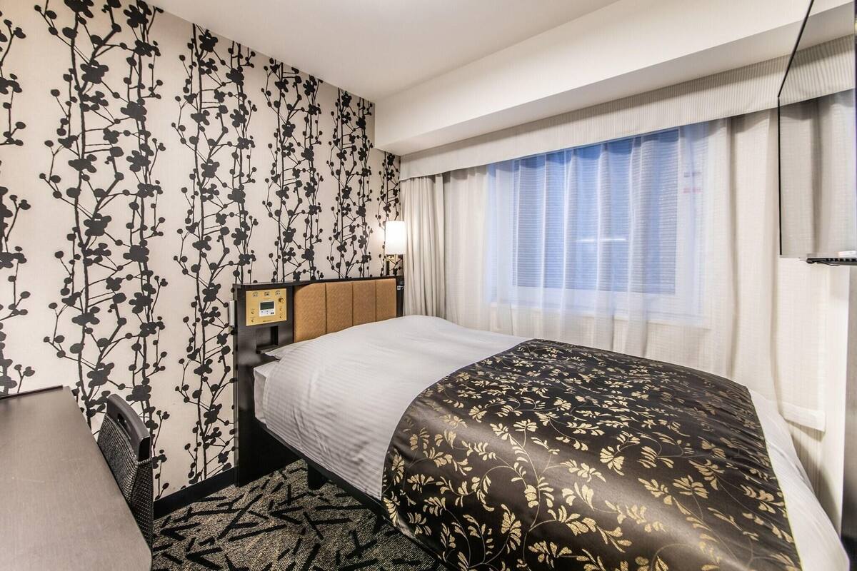 A hotel room with a bed, a desk, and a chair.