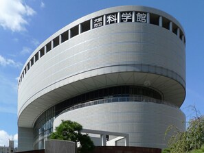 A modern, circular building with a large sign indicating it is a science museum. - APA Hotel Resort Midosuji Hommachi Eki Tower (Osaka)