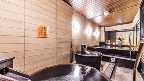 Ein Sauna-Raum mit einer großen schwarzen Wanne, Holzwänden und einem Schild in japanischer Schrift.