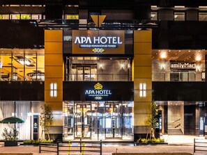 L’hôtel APA se distingue par sa façade moderne, son entrée imposante et la présence d’un magasin FamilyMart bien visible.