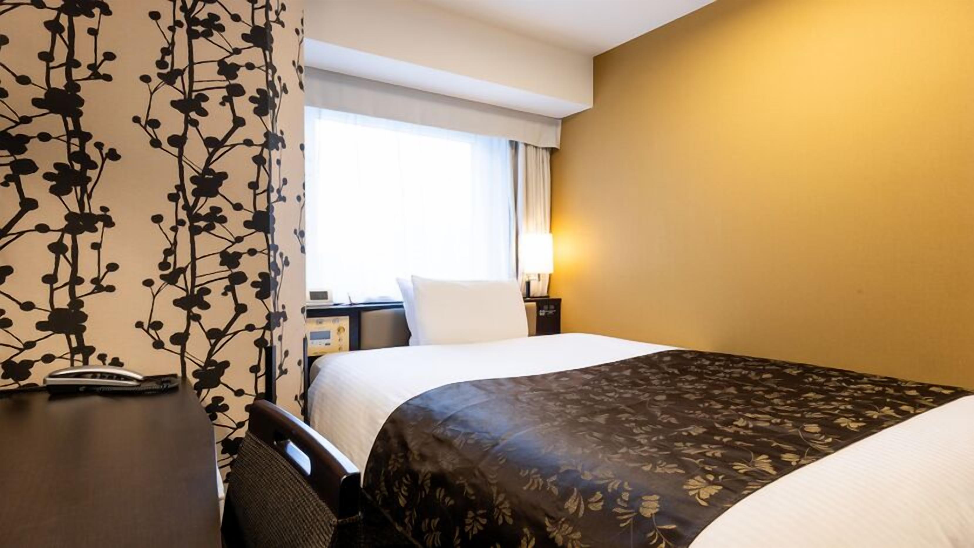 Ein Hotelzimmer mit Bett, Nachttisch, Lampe und einem Vorhangfenster.