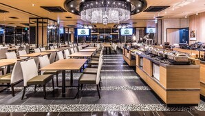 Ein modernes Restaurant mit einer zentralen Kristallleuchtre, langen Tischen und einer Bar.