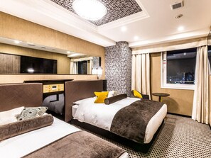 Une chambre d’hôtel avec deux lits, un bureau, un miroir, une fenêtre donnant sur la ville et une moquette à motifs.