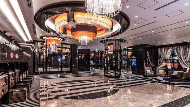 A modern lobby with a central circular staircase, chandeliers, and a seating area with sofas. - APA Hotel Resort Midosuji Hommachi Eki Tower (Osaka)