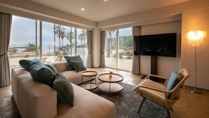 A modern living room with a sofa, two round coffee tables, a chair, and a TV. - Sunshine Sazan Seto (Suooshima)