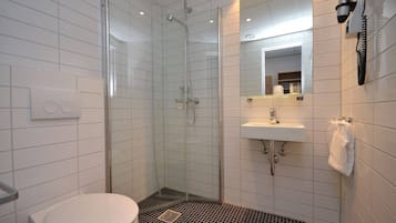 A bathroom with a glass-enclosed shower, a white toilet, a sink, and a mirror.