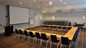 A conference room with a long table, chairs, a projector screen, and a whiteboard.