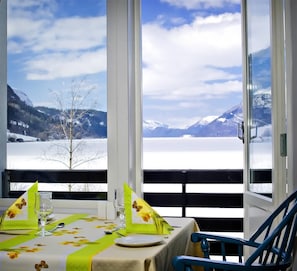 A table set for two with a view of snow-covered mountains and a lake. - First Hotel Raftewold (Volda)