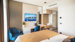 Una habitación de hotel moderna con una cama, un escritorio, una silla y un amplio ventanal con vistas a la ciudad.