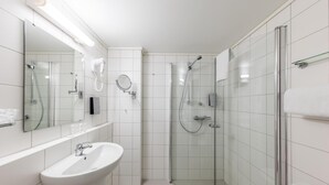 Un baño moderno con ducha acristalada, lavabo blanco y espejo.