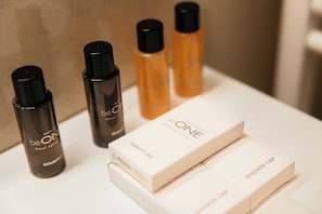 Un ripiano del bagno con prodotti da albergo, tra cui shampoo, kit da toeletta e cuffia per la doccia.