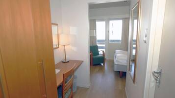 A hotel room with a desk, chair, bed, and a window with curtains.