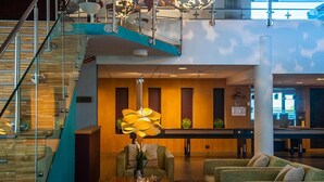 A modern lobby with a staircase, seating area, and a reception desk.