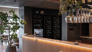 Een receptiegedeelte met een modern design, met een receptiebalie, een potplant en een wijnrek op de achtergrond.