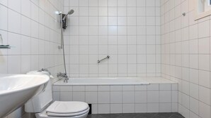 A bathroom with a white sink, toilet, and bathtub, and a showerhead. - Notodden Hotel (Notodden)