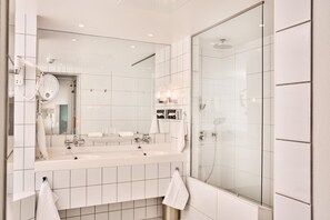 A modern bathroom with a large mirror, two sinks, and a glass shower enclosure. - Ullensvang (Ullensvang)