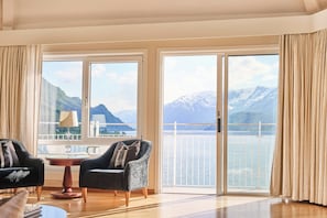 A room with a view of mountains and water, two armchairs, a small table, and a balcony with a railing. - Ullensvang (Ullensvang)