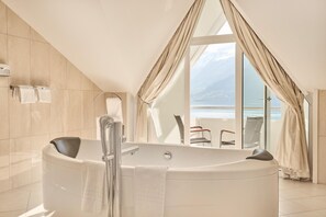 A modern bathroom with a freestanding bathtub, a towel rack, and a large window offering a view of the sea. - Ullensvang (Ullensvang)