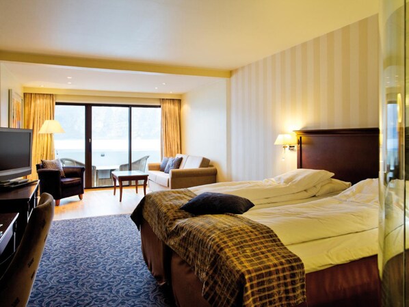 A hotel room with a bed, a sofa, a desk with a TV, and a view of the outdoors. - Ullensvang (Ullensvang)