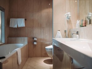 A modern bathroom with a bathtub, toilet, and a large mirror. - Ullensvang (Ullensvang)