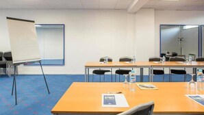 A conference room with a long table, chairs, a flip chart, and water bottles. - Les Gens de Mer (Dunkirk)