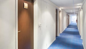 A hotel corridor with a blue carpet, white walls, and a wooden door labeled '208'. - Les Gens de Mer (Dunkirk)