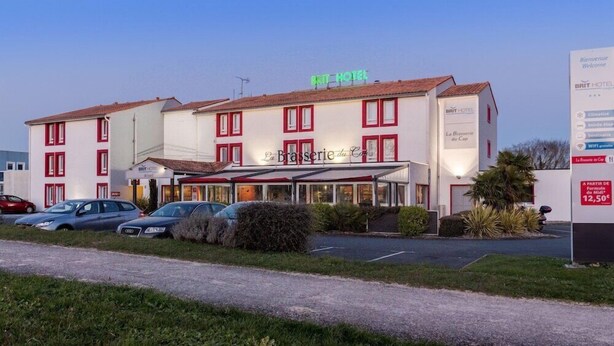 Un hôtel à la façade rouge et blanche, doté de nombreuses fenêtres et d’une enseigne indiquant un prix de 12,50 € la nuit.