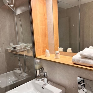 A modern bathroom with a glass-enclosed shower, a wooden vanity, and a large mirror. - The Originals Beziers Est Le Pavillon (Villeneuve-les-Beziers)