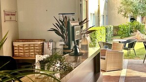 Ein Empfangsbereich mit einer Rezeption, einer Kaffeemaschine und Korbmöbeln.