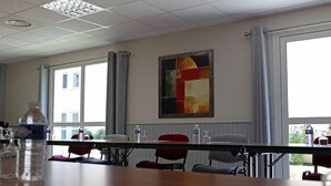 Ein Konferenzraum mit großem Fenster, einem Tisch mit Stühlen und einem Gemälde an der Wand.