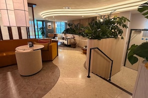 A hotel lobby with seating areas, a reception desk, and large potted plants. - Modern City Apartment in Manchester (Manchester)