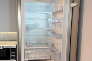 A refrigerator with multiple shelves and a built-in ice maker. - Modern City Apartment in Manchester (Manchester)