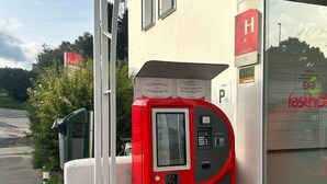 Un parcometro rosso davanti a un edificio con un cartello che riporta la scritta "Fastfood".