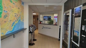 Un'area reception di un hotel con una mappa appesa al muro, un banco informazioni e un frigorifero.